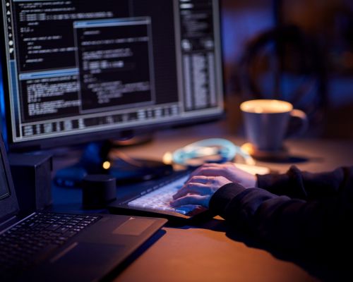 hands typing on keyboard in front of two computer screens