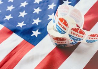 roll of "I voted" stickers on top of an American flag